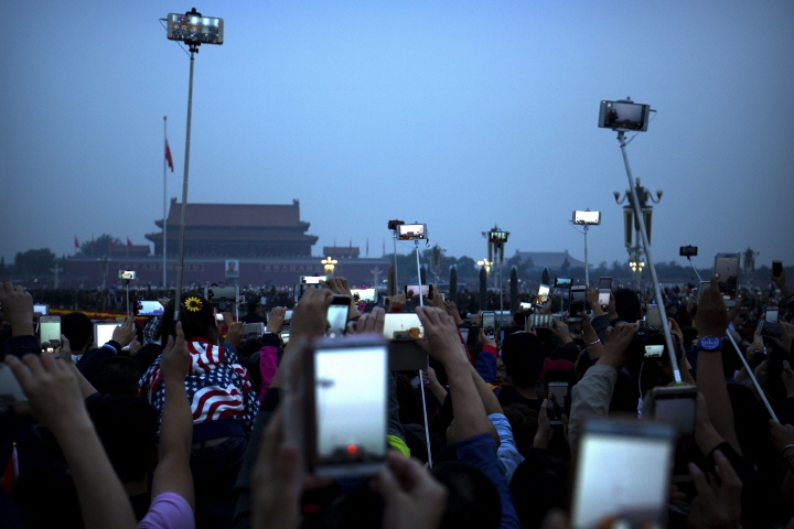 10월 1일 중국 국경절 아침 오성홍기가 게양되는 것을 중국인들이 스마트폰으로 기념촬영하고 있다. [사진=연합뉴스]