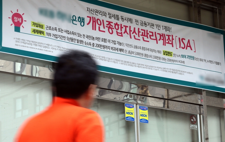 한 시민이 ISA계좌 홍보물이 부착된 서울시내 은행 지점 앞을 지나고 있다. [사진=연합뉴스]