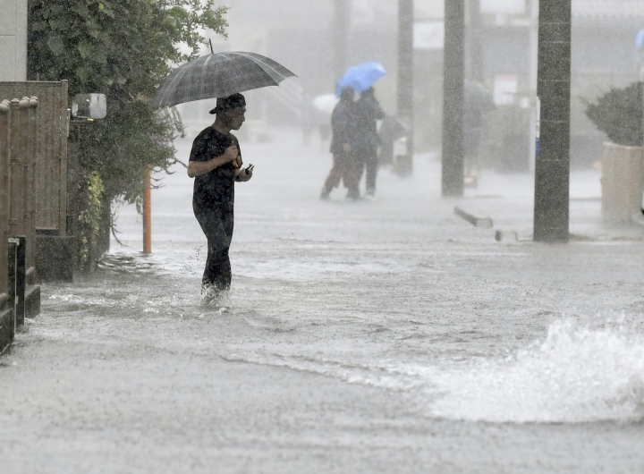 12일 제19호 태풍 하기비스의 영향으로 폭우가 쏟아진 일본 시즈오카(靜岡)시의 도로가 물에 잠긴 가운데 행인이 걸어가고 있다. [사진=연합뉴스]