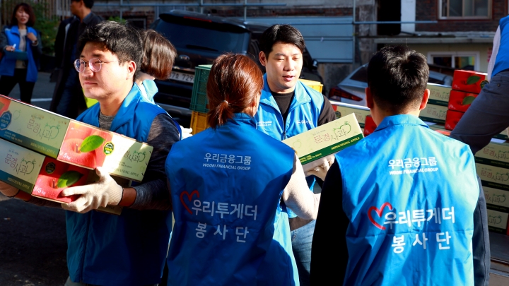 우리카드 임직원들이 25일 서울 중구 남대문 쪽방촌에서 햇사과 전달 행사를 실시하고 있다. [사진=우리카드]