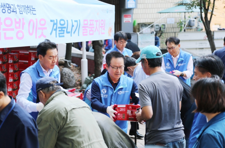 신한생명 임원 봉사자들이 서울역 쪽방상담소 나눔터에서 쪽방촌 거주민들에게 라면박스를 전달하고 있다. [사진=신한생명]