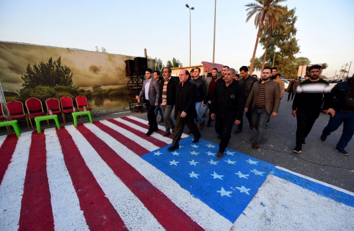 이라크의 친(親)이란 시아파 민병대 지지자들이 지난 2일 바그다드 주재 미국 대사관 인근 길바닥에 그려진 미국 국기를 밟고 지나가고 있다. [사진=연합뉴스]