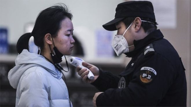 중국 우한에서 보안요원이 보행자의 체온을 측정하고 있다.
