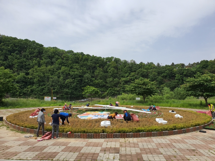 지난 14일, 내일동 관계자들이 암새들 일원에 여름꽃인 페츄니아를 식재하고 있다. [사진=밀양시]