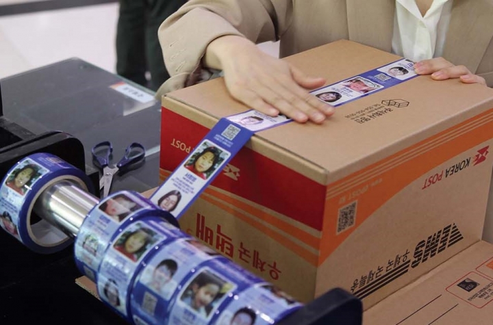 서울 강남 우체국에서 시민들이 장기 실종아동 정보가 인쇄된 ‘호프테이프’를 이용해 택배상자를 밀봉하고 있다. [사진=우정사업본부]