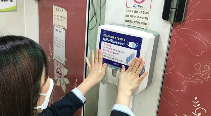 성남시 공무원이 공중화장실에 생활속 거리두기 점검을 나가 안내문을 붙이고 있다. [사진=성남시]