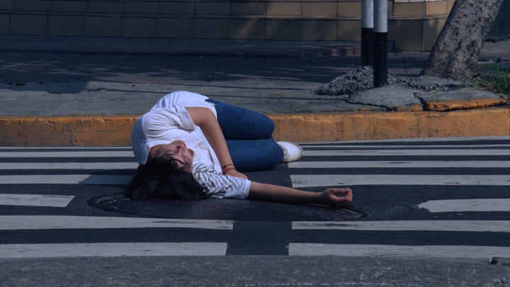 소년은 길에 쓰러져 있는 소녀를 촬영한다. [사진=영화 '공포분자']