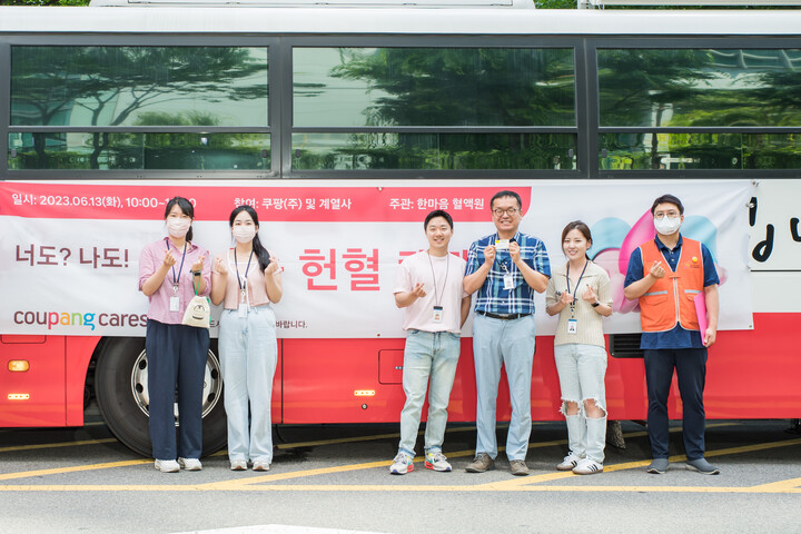 쿠팡∙쿠팡 자회사 임직원들이 서울 잠실 사옥 주변에 마련된 헌혈버스 앞에서 기념 촬영을 하고 있다.  [사진=쿠팡]