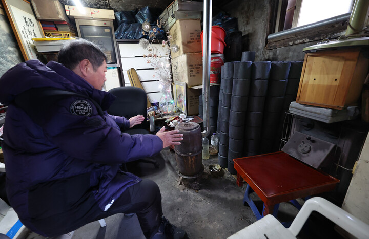 지난 겨울 서울 서대문구 홍제동 개미마을에서 한 주민이 연탄보일러로 추위를 녹이고 있다. [사진=연합뉴스]