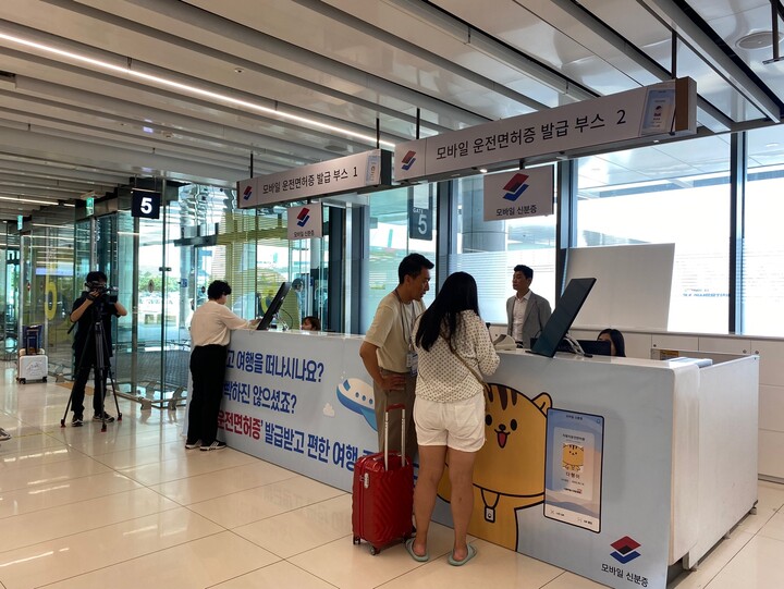 김포공항을 방문한 탑승객들이 직원들의 도움을 받아 모바일 면허증을 발급받고 있다. [사진=정희경 기자]