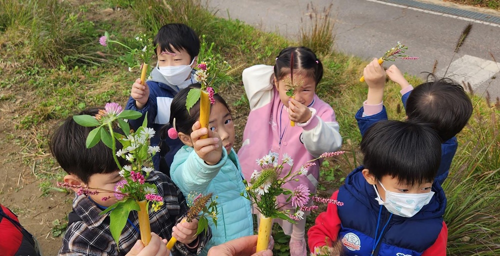 성남지역 유치원생들이 수내습지생태원에서 붉은 토끼풀, 개망초 등 주변 식물을 이용해 자연화병 만들기를 하고 있다. [사진=성남시]